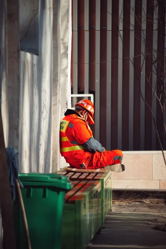 Tradesman in safety gear sitting idle, no work today